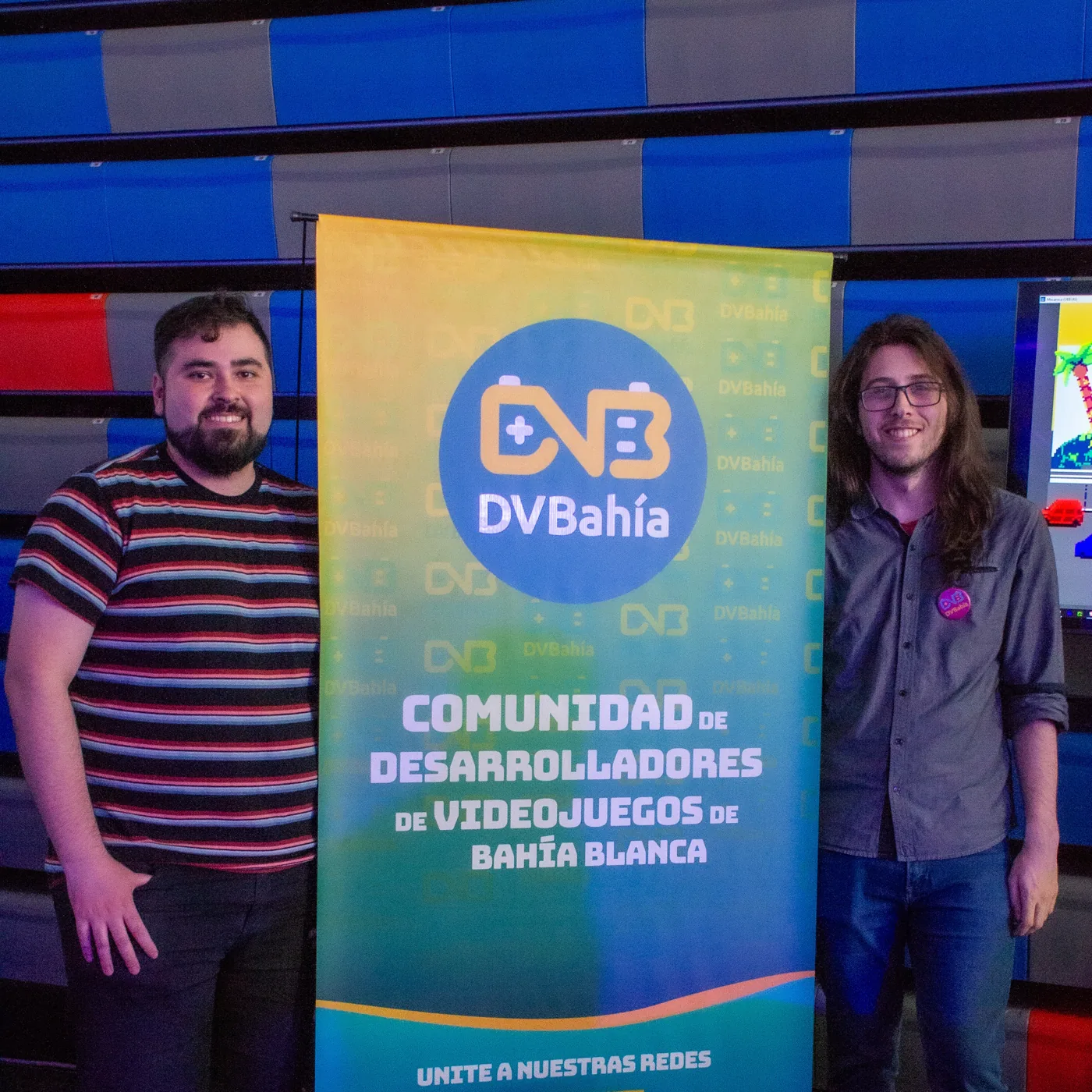 Dos integrantes junto al banner de DVBahía
